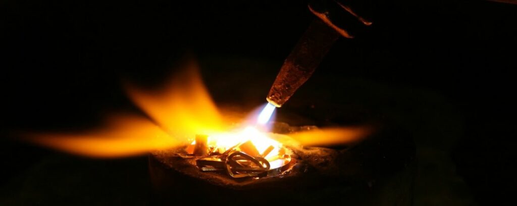 A close up of a blow torch melting coins