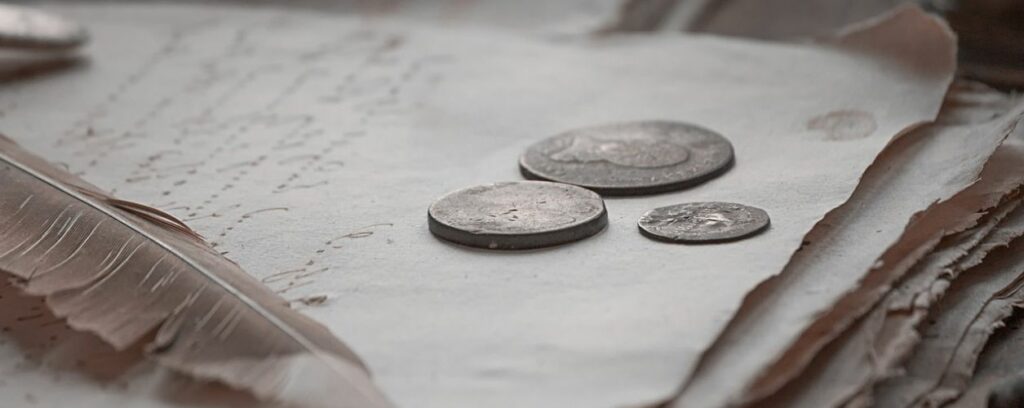 Three old US coins sitting atop parchment paper.
