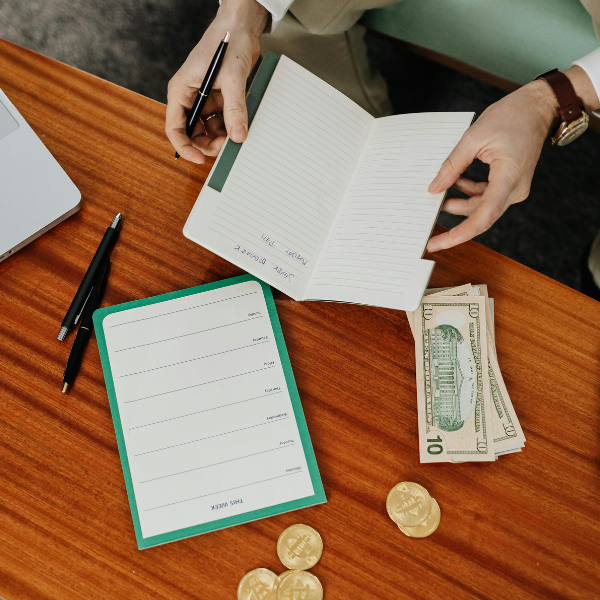 Person sitting down with notebook and coins